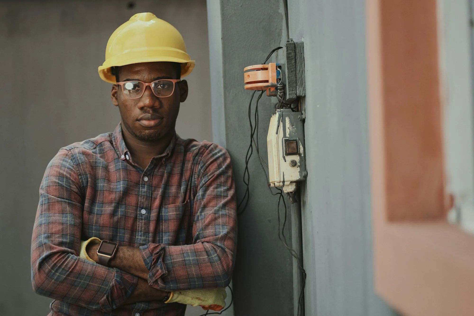 Electrician in a hard hat and safety glasses standing by a service panel