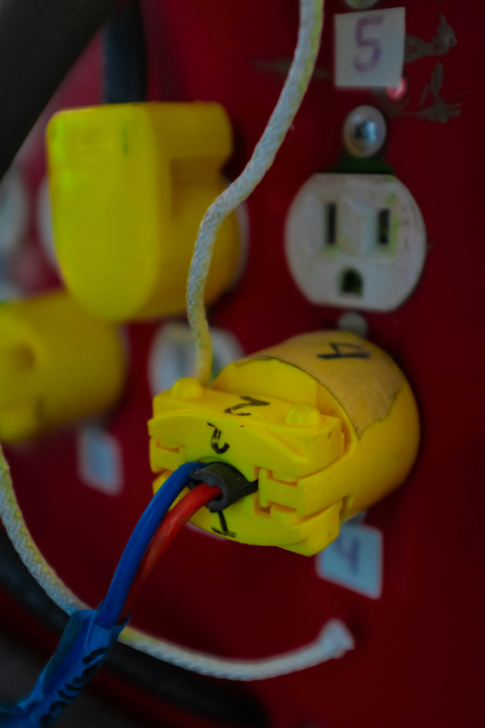 Yellow plug pushed into a red wall outlet