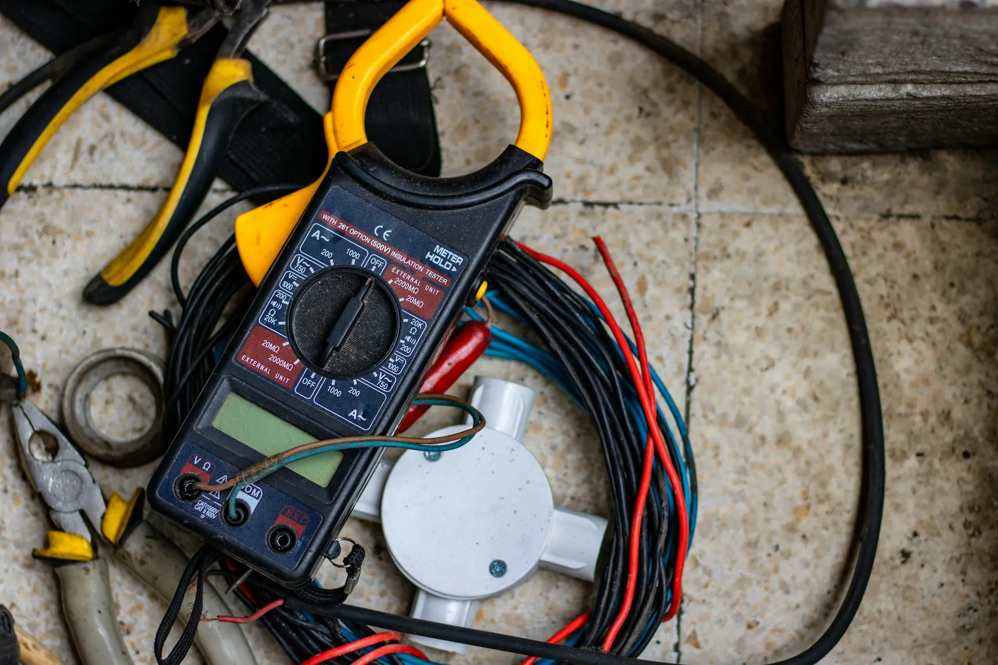 Multimeter with test leads resting on coiled electrical wire
