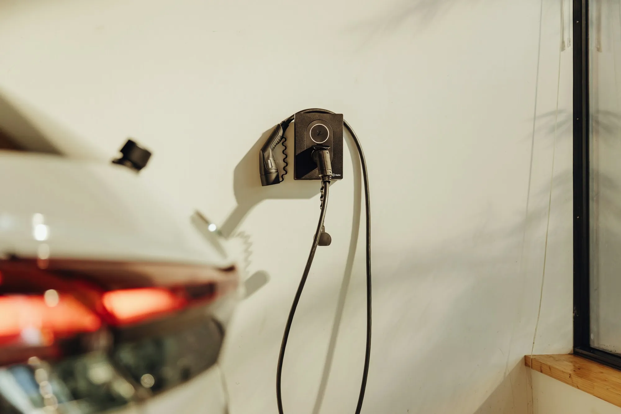 Electric car parked beside a wall-mounted home charging unit