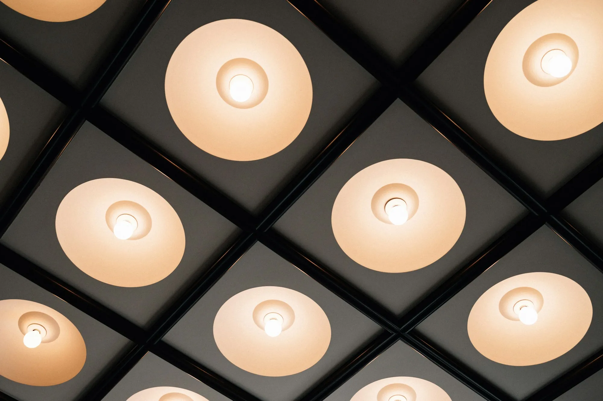Grid of warm recessed ceiling lights in a dark ceiling