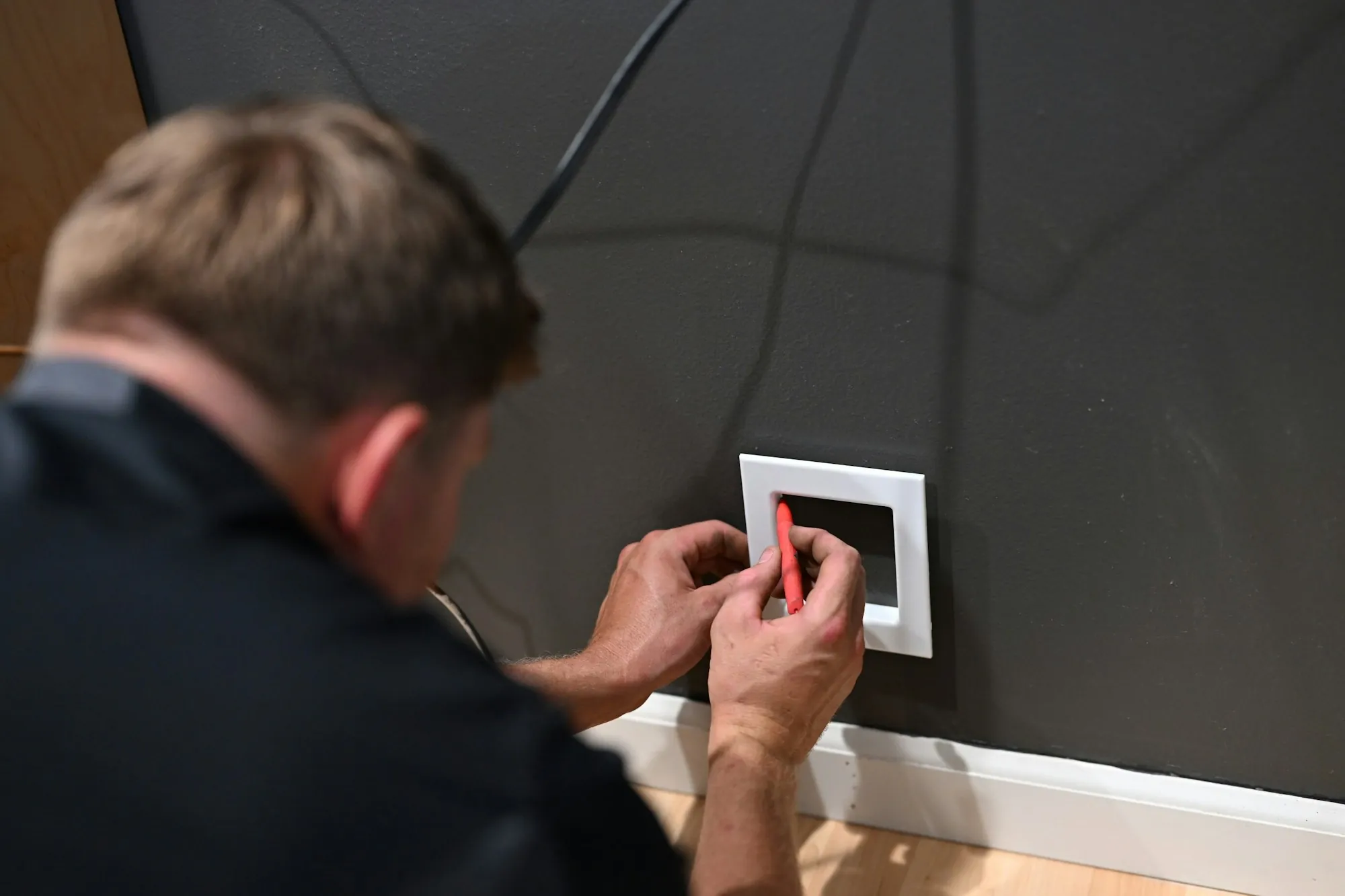Electrician fitting a new wall plate over a fresh switch box